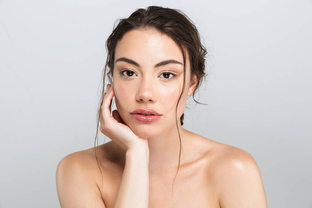 Beauty portrait of a pretty young topless woman with make up looking at camera isolated over gray background - Photo, Image