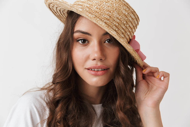 Close up portrait of a lovely young casual brunette woman in hat posing looking at camera isolated over white background - Foto, Imagem