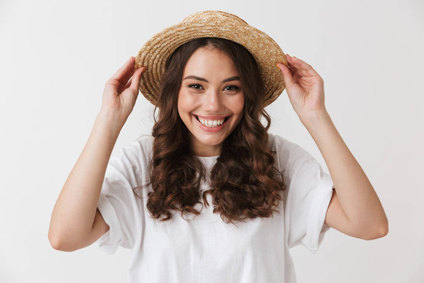 Close up portrait of a cheerful young casual brunette woman in hat posing looking at camera isolated over white background - Фото, зображення
