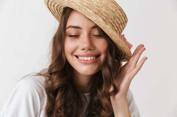 Close up portrait of a smiling young casual brunette woman in hat posing looking at camera isolated over white background - Фото, изображение