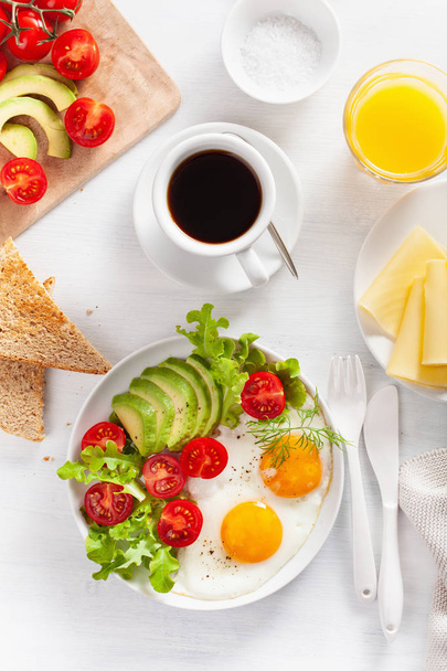 healthy breakfast flat lay. fried eggs, avocado, tomato, toasts and coffee - Fotó, kép