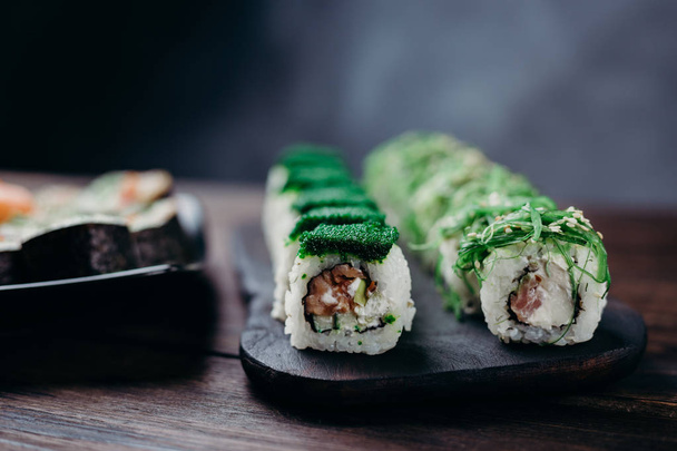 Traditional Japanese sushi rolls on dark plate - 写真・画像