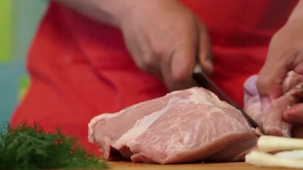 The cook in a red apron cuts pieces a fresh product for cooking. - Záběry, video