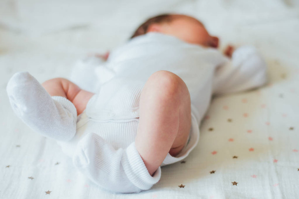 Маленькі ноги новонародженої дитини в білих шкарпетках
  - Фото, зображення