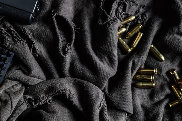 Цельнометаллическая куртка пуля калибра 9 мм на тканевой текстуре
 - Фото, изображение