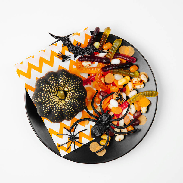 Black plate with Halloween candies and decorations - 写真・画像