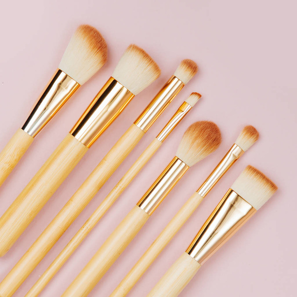 Fashion various makeup brushes on a pastel pink background. Flat lay, top view - Foto, imagen