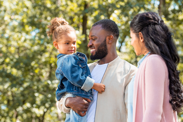 πορτρέτο της ευτυχείς γονείς αφροαμερικάνων και κόρη στέκεται μαζί στο πάρκο - Φωτογραφία, εικόνα