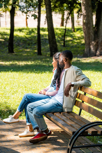 Αφρικανική αμερικανική ζευγάρι κάθεται στο ξύλινο πάγκο στο πάρκο και αναζητούν μακριά - Φωτογραφία, εικόνα
