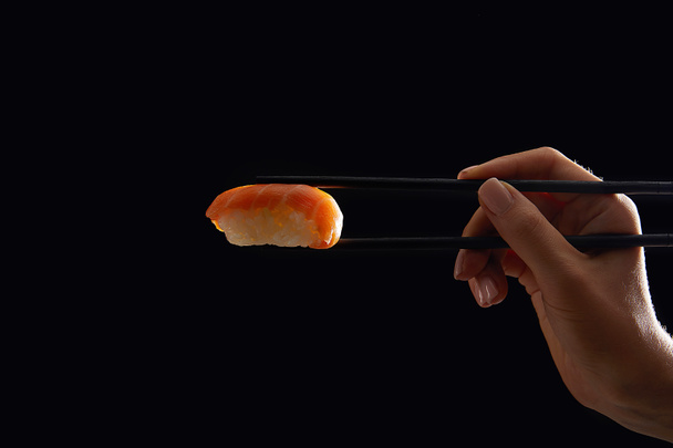 oříznuté horké ženy držící nigiri sushi s lososem, samostatný na černém - Fotografie, Obrázek