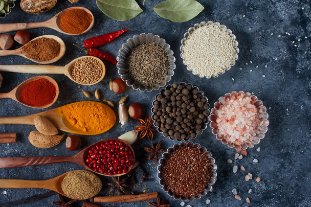 Various Indian spices in wooden spoons and metal bowls - Fotó, kép