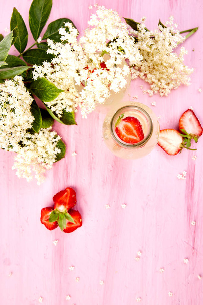 Kombucha thee met Vlierbes bloem en aardbei op roze achtergrond. Homemade gefermenteerde geïnfundeerd drankje. Zomer gezonde natuurlijke probiotische smaak drinken. Kopieer ruimte. Bovenaanzicht. - Foto, afbeelding