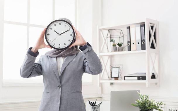 Woman in hijab covering face with clock - Photo, Image
