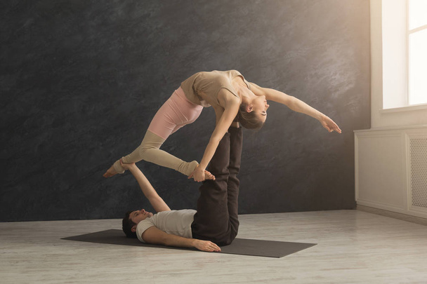 Young couple practicing acroyoga on mat together - Fotó, kép