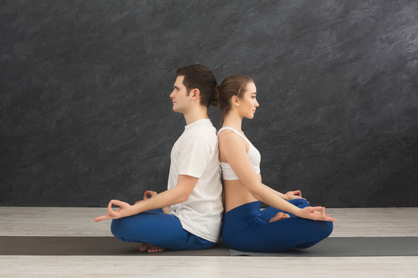 Молодая пара медитирует вместе, спина к спине
 - Фото, изображение