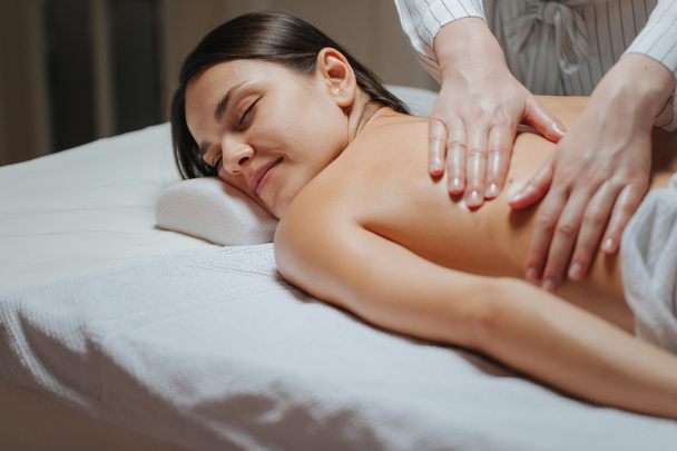 Mujer joven disfrutando de un masaje de espalda en un centro de spa
. - Foto, Imagen