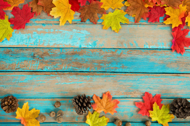Beautiful frame composed of  autumn maple leaves with pine cones on wood plank. nature fall season background. - Photo, Image