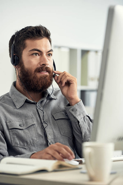 Telefonla satış merkezi arama operatörü olarak çalışan ve istemci kulaklık ile konuşan sakallı adam - Fotoğraf, Görsel