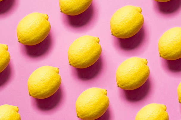 Yellow lemons on pink background - Foto, imagen