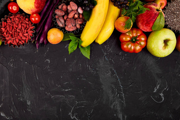 Zdrowe jedzenie kolorowy wybór: owoców, warzyw, nasion, pożywienie, fasola, liść warzywo na ciemnym tle. Czyste, jedzenie. Wegańskie. Detox. Produktów w supermarkecie zawierająca asortyment świeżych organicznych naturalnych pojęcie  - Zdjęcie, obraz