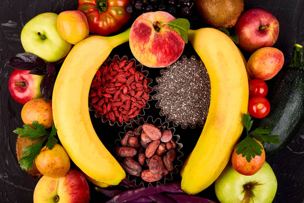 Terveellinen värikäs ruokavalikoima: hedelmät, vihannekset, siemenet, superruoka, pavut, lehtivihannekset tummalla taustalla. Puhdasta ruokaa. Vegaani. Vieroitushoitoa. Supermarket tuote Valikoima Tuore Organic Natural Concept
  - Valokuva, kuva