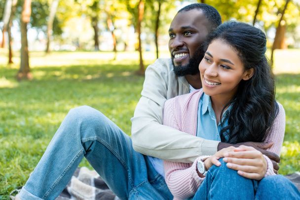 smiling african american boyfriend hugging girlfriend in park  - Fotó, kép