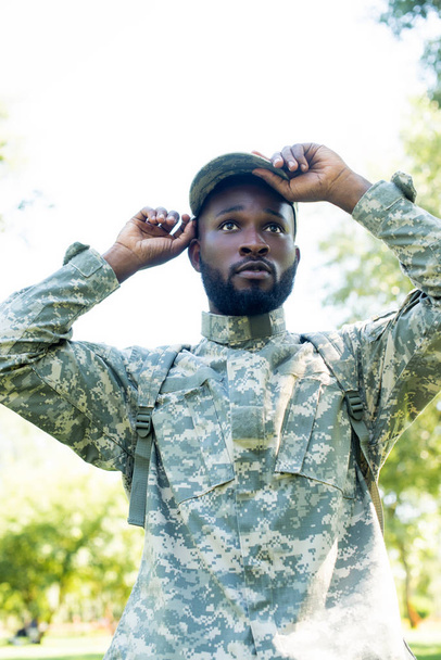 όμορφος Αφρικανικός Αμερικανός στρατιώτης με στρατιωτική στολή, φορώντας το καπάκι στο πάρκο - Φωτογραφία, εικόνα