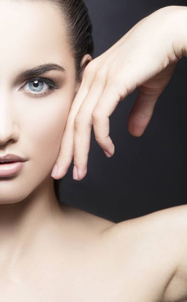 Oříznutý portrét krásné ženy s přírodní make-up dotýkání tváře ručně - Fotografie, Obrázek