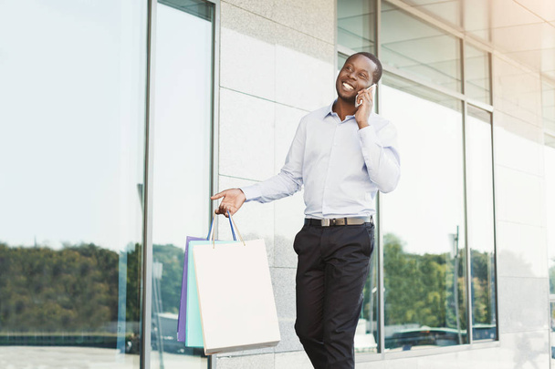 Black businessman carrying shopping bags - Fotó, kép