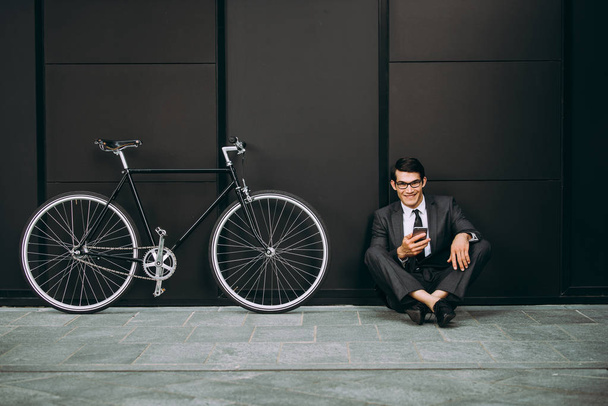 Handsome young business man with his modern bicycle. - Фото, зображення