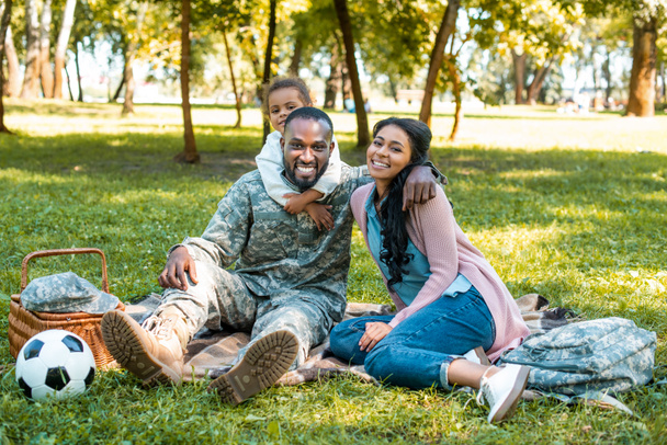 boldog afro-amerikai katona ül a fűben a család, a park - Fotó, kép