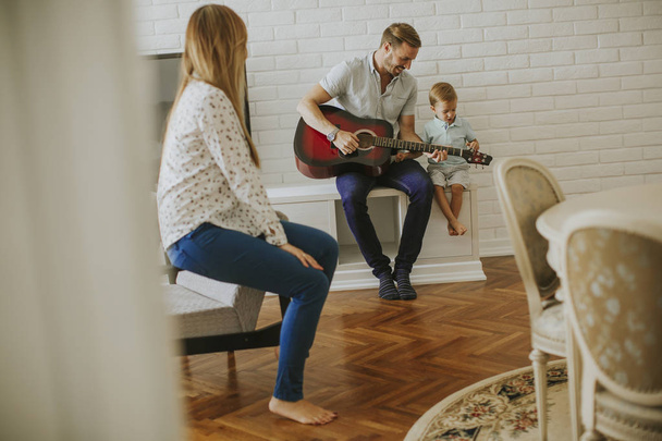 Happy family with guitar at home - Foto, afbeelding