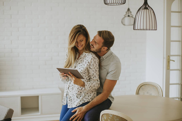 Couple utilisant une tablette numérique ensemble dans le salon à la maison
 - Photo, image