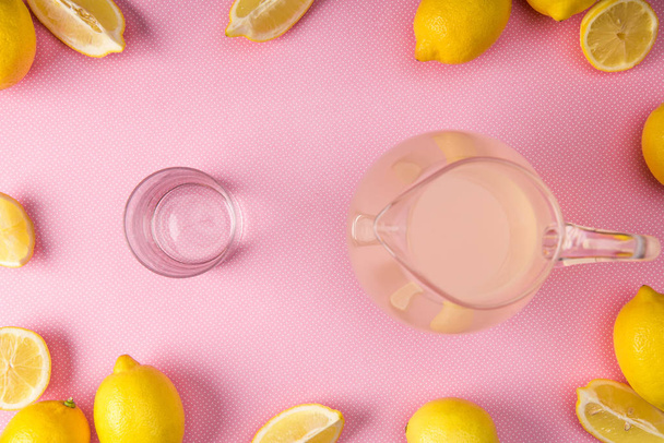 limon ile pembe arka plan üzerinde cam ve sürahi taze meyve suyu ile üstten görünüm - Fotoğraf, Görsel