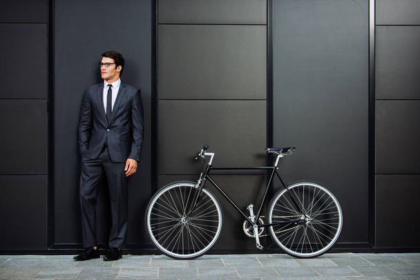 Handsome young business man with his modern bicycle. - Фото, зображення