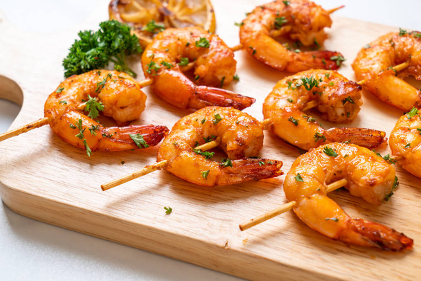 Grilled tiger shrimps skewers with lemon - 写真・画像