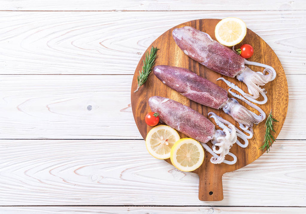 fresh octopus or squids raw on wooden board with ingredients - 写真・画像