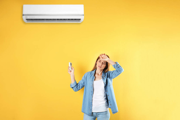 Woman operating air conditioner on color background - Foto, imagen