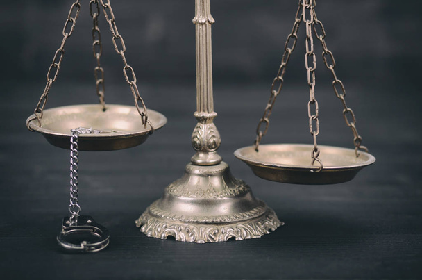 Droit et justice, concept de légalité, échelles de justice et menottes sur fond de bois noir. - Photo, image