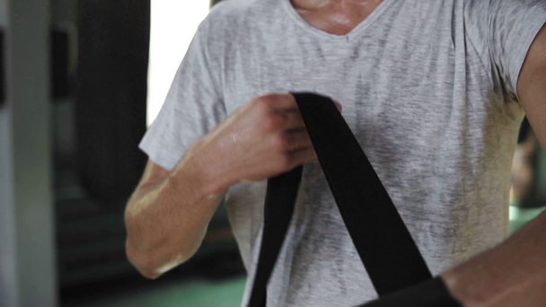Zbliżenie męskich rąk bokser otacza bandaże bokserskie czarny. Pięści Fighter przed walka lub trening w siłowni sport - Materiał filmowy, wideo