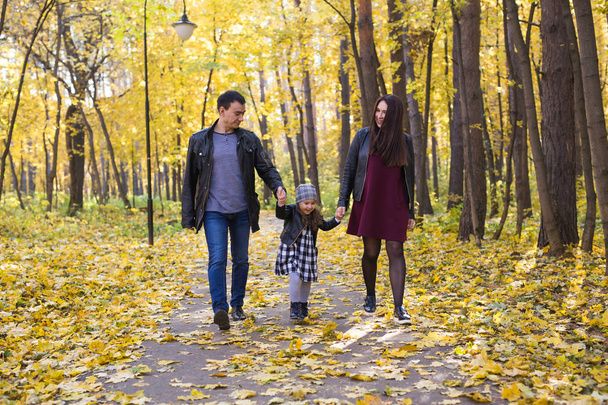 ihmiset, perhe ja vapaa-ajan konsepti - perhe, jossa nuori tytär kävelee syksyllä puistossa
 - Valokuva, kuva