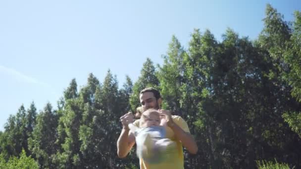 Young father throwing up his little daughter outdoors. - Video
