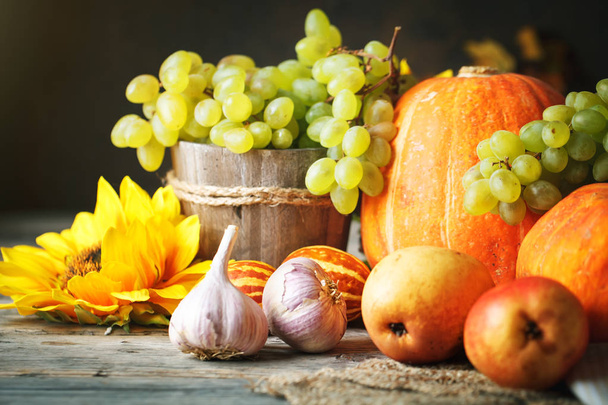 Деревянный стол, украшенный тыквой, кукурузой, фруктами и осенними листьями. Праздник урожая. Выборочный фокус. Горизонталь
. - Фото, изображение