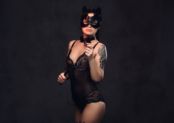 Bdsm aksesuarları ve karanlık bir arka plan üzerinde poz kedi deri maske siyah iç çamaşırı giyen baştan çıkarıcı şehvetli hanım kız. Karanlık bir arka plan üzerinde izole.    - Fotoğraf, Görsel