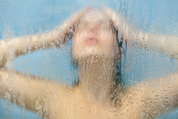 Relief and relaxation concept. Female model washes hair in douche, stands in shower cabine at bathroom, applies shampoo, closes eyes as feels relaxed and carefree, rests after hard work - Foto, afbeelding