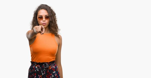 Mladá žena hispánský na sobě letní oblečení, ukazující prstem na kameru a na vás, rukou znamení, pozitivní a sebevědomý gesto z přední - Fotografie, Obrázek