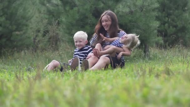 Mama bawi się z dziećmi w parku na trawie - Materiał filmowy, wideo