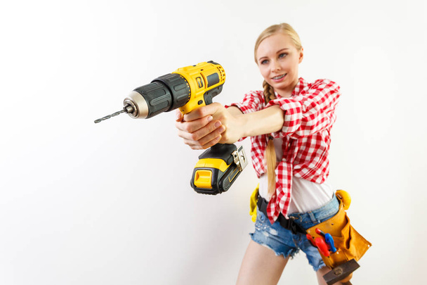 Young determinated woman using drill doing home renovation. Female construction worker having driller tool drilling wall. - Valokuva, kuva