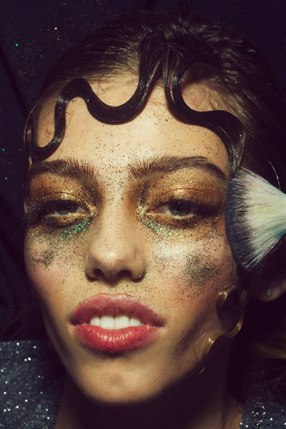 Pretty fashion girl putting holiday glitter makeup - Фото, изображение