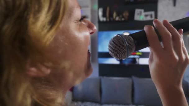 Close up. a woman screaming to a microphone. a woman sings karaoke into a microphone in a home setting. 4k, slow motion - Materiał filmowy, wideo